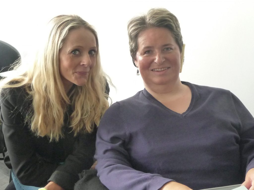 Photo de deux femmes assises côte à côte, vues de face